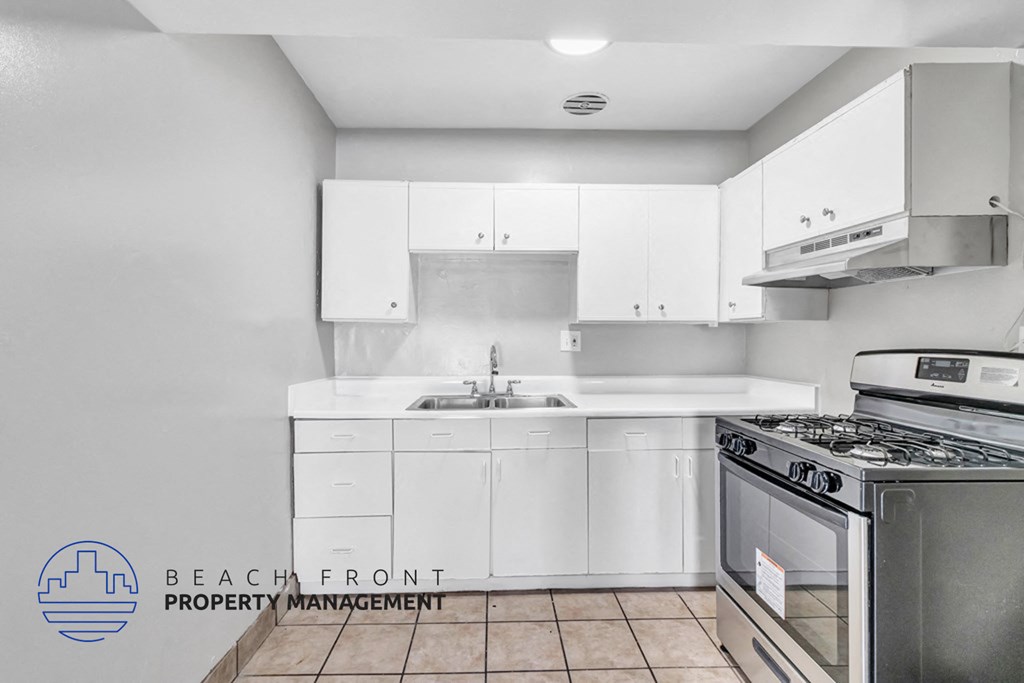 A kitchen with white cabinets and a stove top oven.